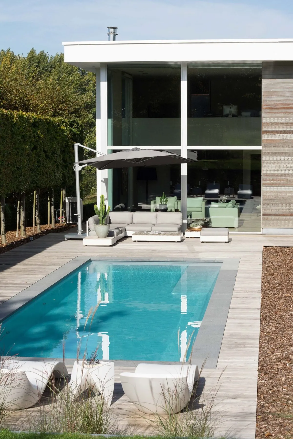 Pool mit Abdeckung und Treppe vor Holzhecke